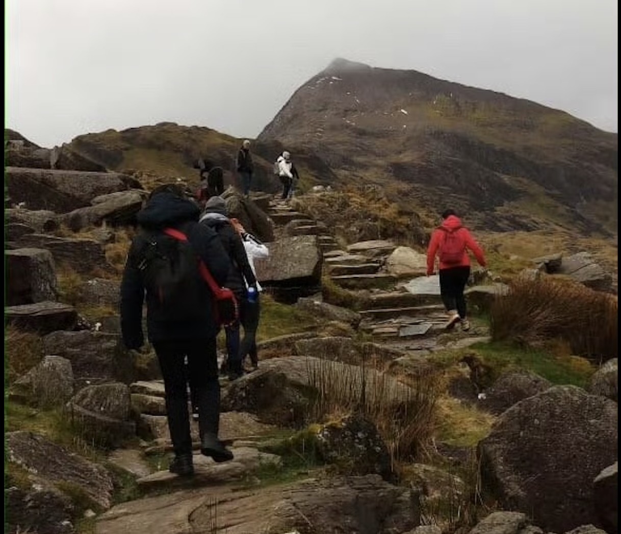Peiyu hiking with a group along a rocky mountain trail